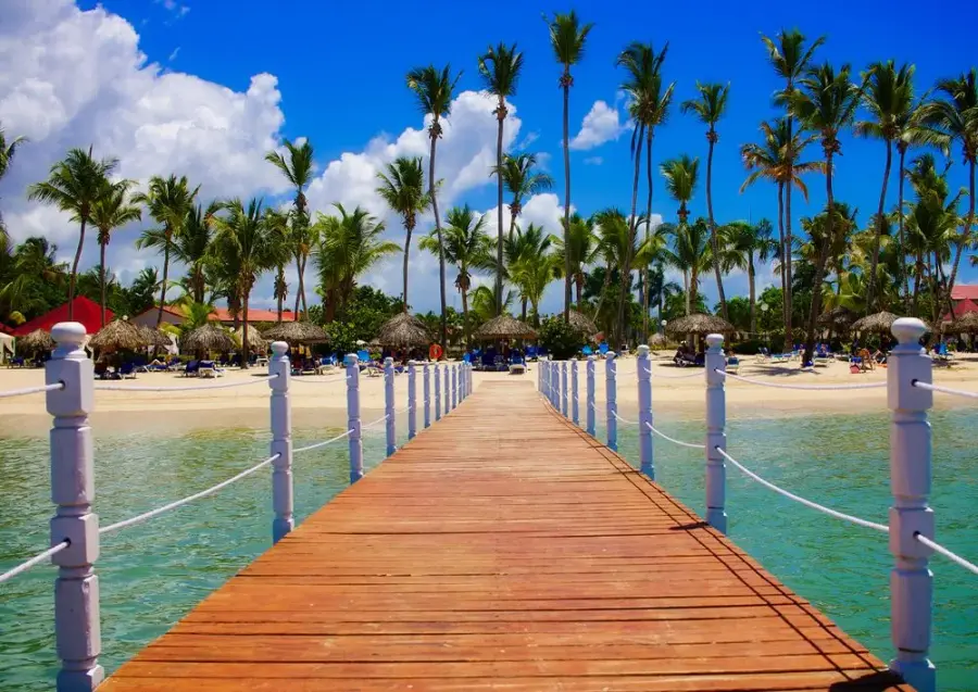 Palm-lined Punta Cana beach and a wooden jetty over clear Caribbean water