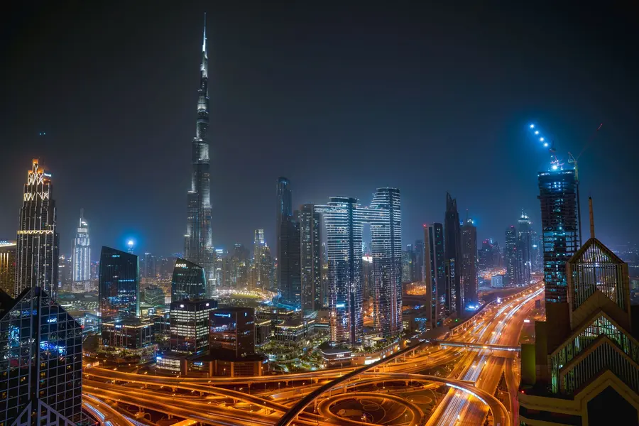 Dubai skyline at night with the illuminated Burj Khalifa and golden city roads