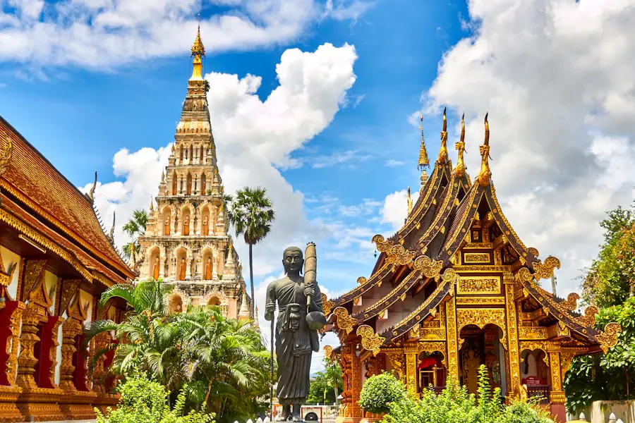 Golden Thai temple roofs and ornate architecture beneath a blue sky